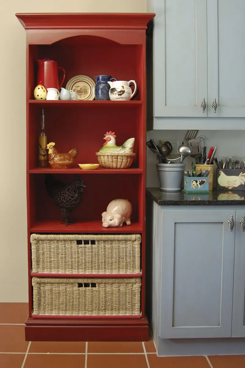 Red kitchen hutch next to light pastel blue rustic kitchen cabinets with brown 12x12 tile flooring