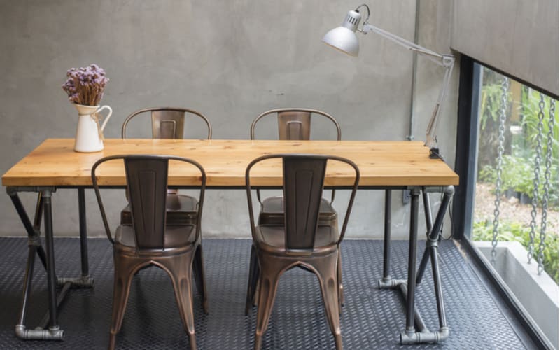 Industrial styling idea that mixes a natural wood table with metal chairs and a metal table leg made out of metal pipe