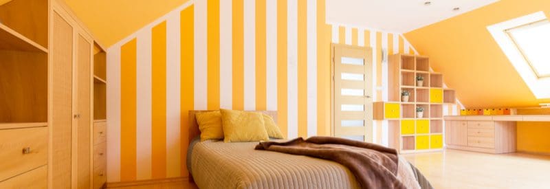 Teen boy room decorating idea with bold yellow vertical striped and natural wooden bookshelves with yellow inserts