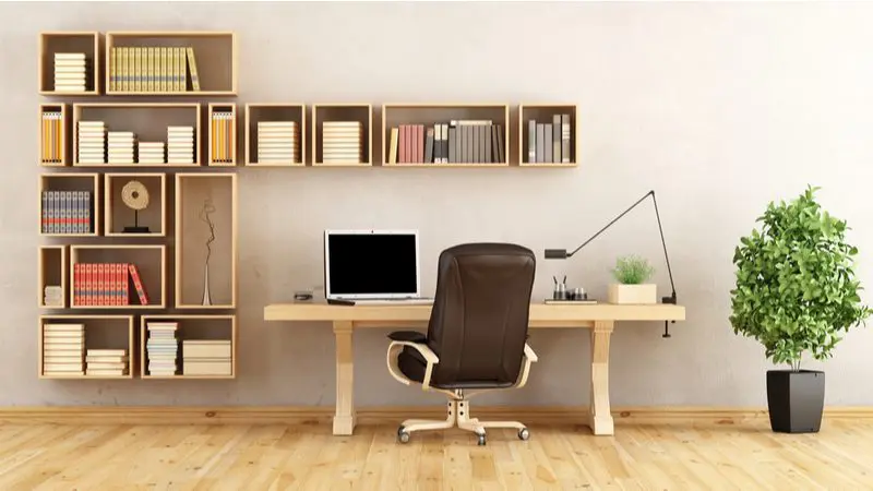 Image of a home office design idea featuring wall-mounted cabinets above and to the left of a heavy wooden desk