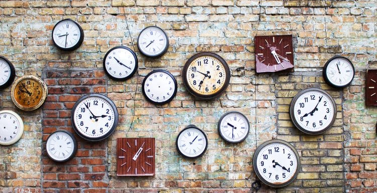 Featured image for a piece titled Types of Clocks featuring several analog clocks in different finishes and styles mounted to a brick wall