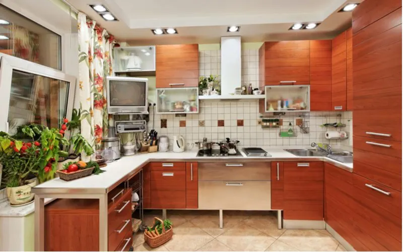 Medium brown wood cabinets with horizontal grain and stainless steel pulls and white counters in a retro-euro kitchen