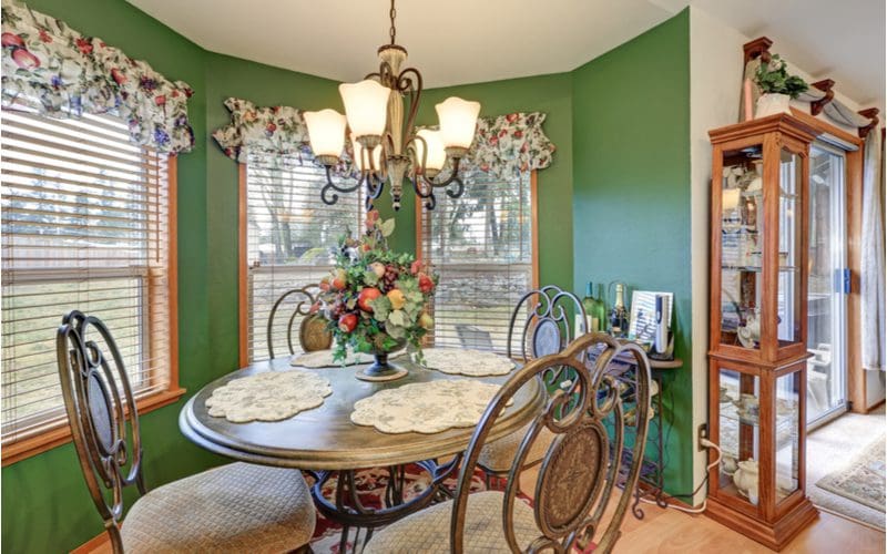 Ugly green breakfast nook idea that you'd likely find in your grandma's house with oak wood trim and farmhouse-style fabric window valances