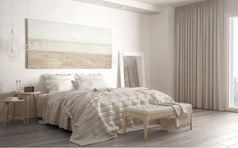 Transitional bedroom with light grey wood floors, white walls, beige curtains, and soft accents