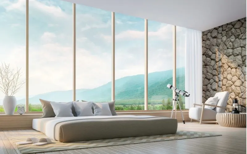 Bay window curtain idea on floor-to ceiling windows featuring sheer white curtains next to a stone façade wall