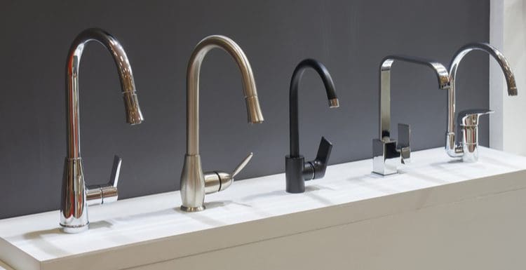 Image for a piece on best faucet brands featuring several high-rise kitchen faucets in several brands in a row against a black wall
