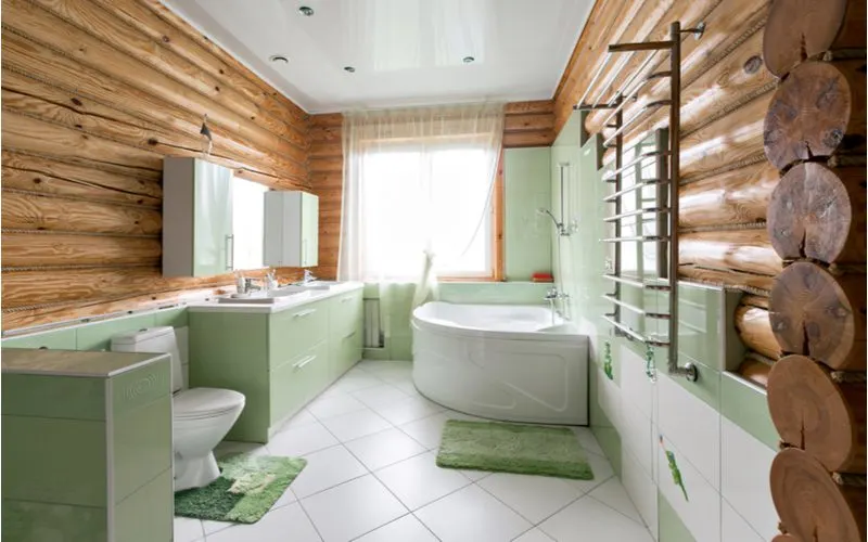 Rustic Iron Towel Rack in a log cabin-style bathroom with green cabinets and recessed lighting attached to a shiny white ceiling