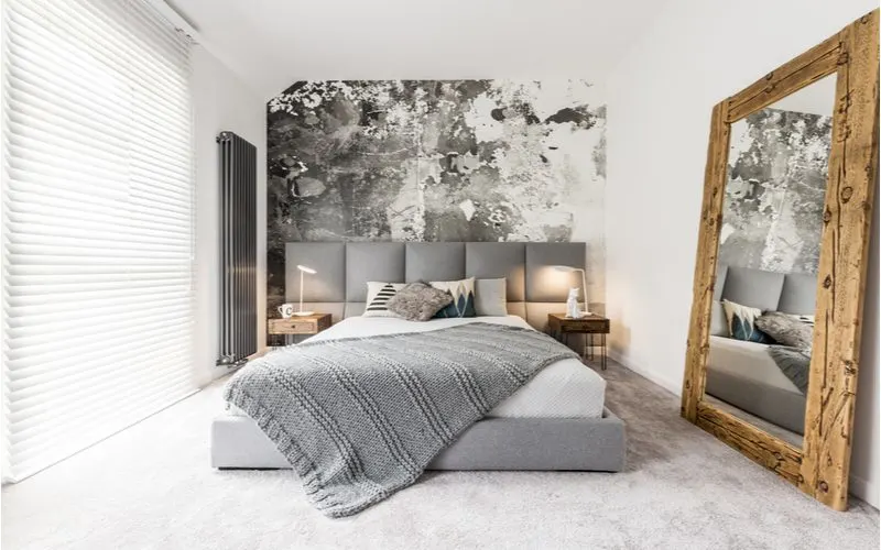 Wall-Sized Mirror leaning against the white wall in a bedroom with simple white walls and a grey and black blotted accent wall
