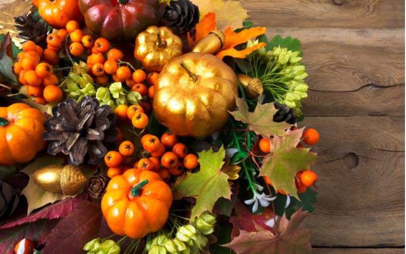 Idea for a fall centerpiece featuring a gold wreath made of pumpkins and cranberries