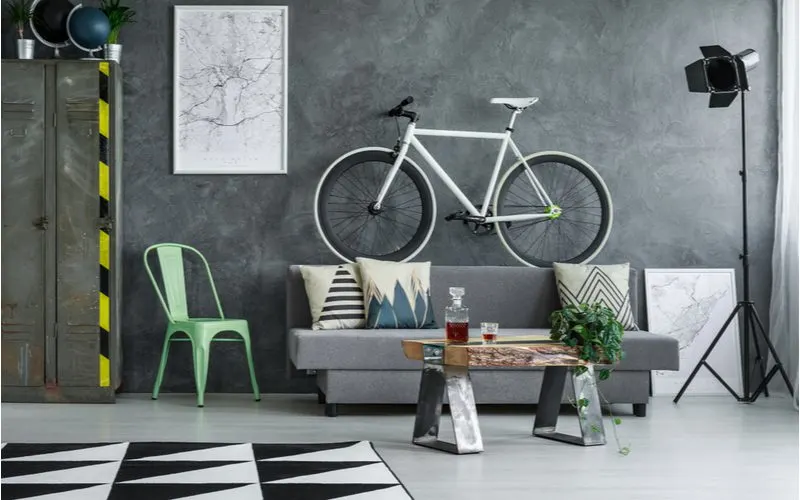 Bachelor pad idea featuring a bike hanging on the wall of a neutral living room with dark grey textured walls and cement floors decorated in a somewhat rustic style