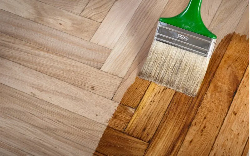 To help answer what color wood floor goes with dark cabinets, a person staining a neutral color onto a parquet floor