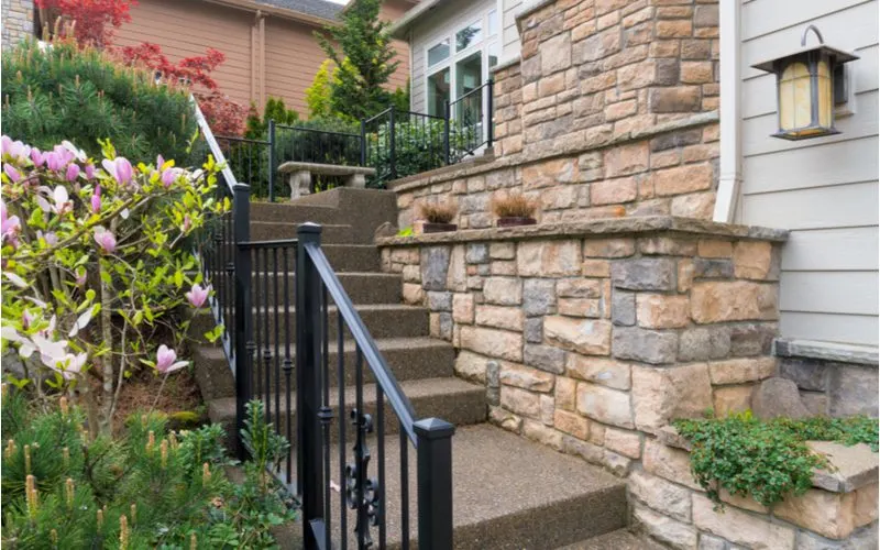 Natural Stone Cladding (one of the types of stone siding) on the walkway to a home across from a stair railing