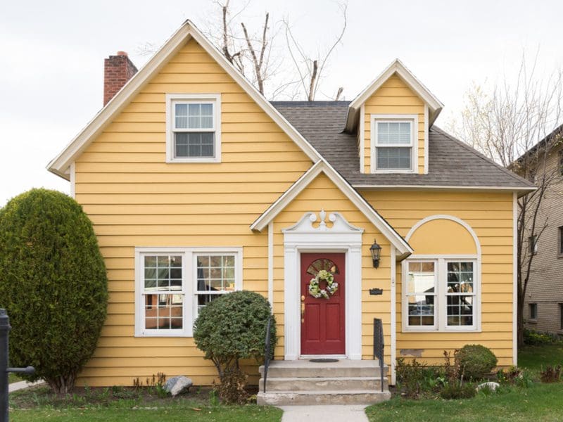 Brick red, one of the best front door colors for yellow houses