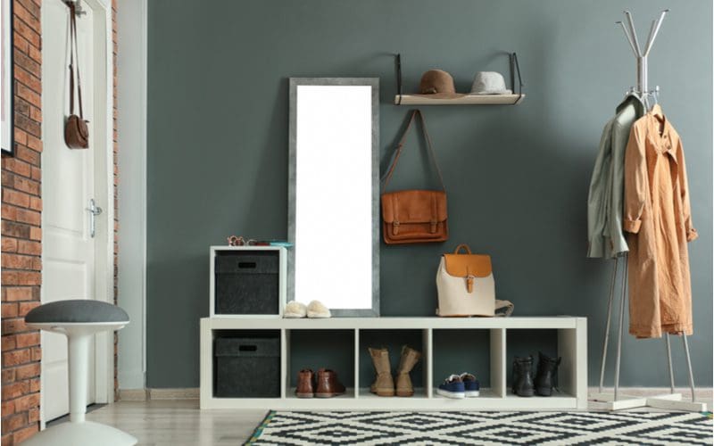 Example of room ideas featuring a green-gray wall with wooden cubbies and a metal coat rack next to the front door