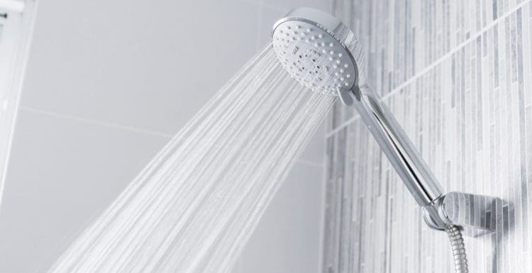 Image for a piece titled How to Increase Water Pressure in Shower featuring a showerhead with water flowing out of it at an extremely high rate