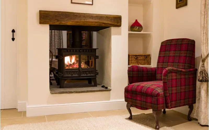 Average fireplace mantle height featuring a red and black plaid chair in front of a tan fireplace with a dark stained wood mantle
