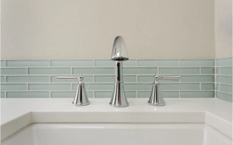 Example of one of our favorite room ideas featuring blue glass subway tile behind a faucet