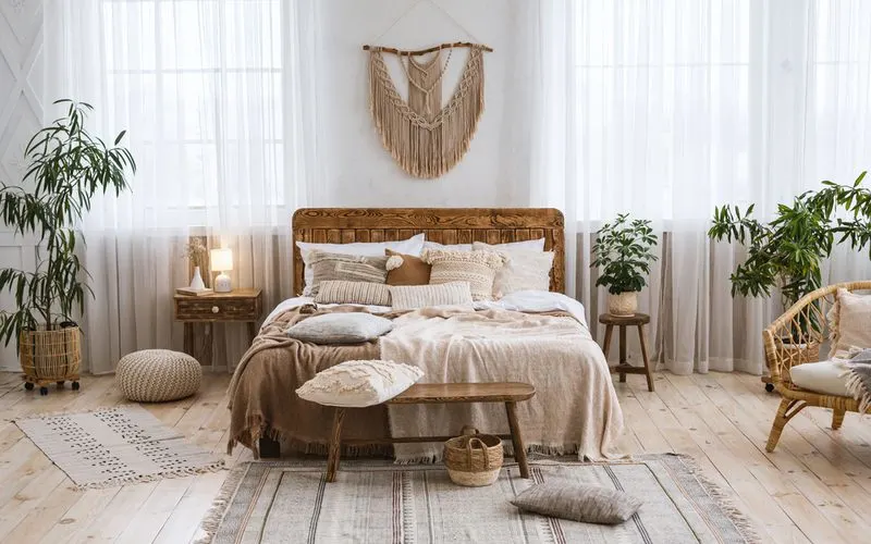 One of the best room ideas, a boho style bedroom with hanging tapestries and lots of weaved wooden furniture and planters