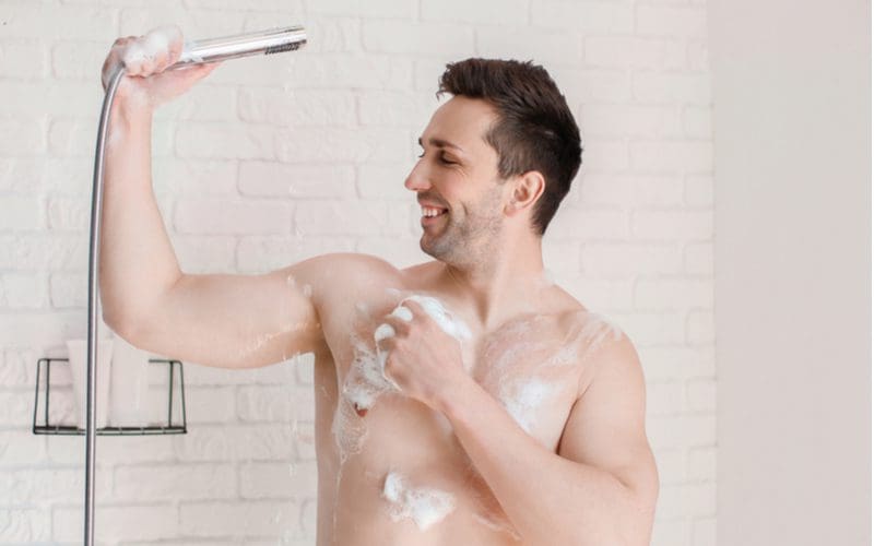 Guy using a handheld shower sprayer because his shower head height is too low