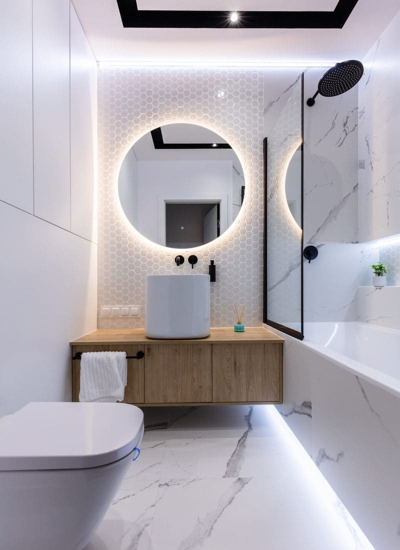 Small bathroom with tub idea featuring a round mirror and a glass half shower wall