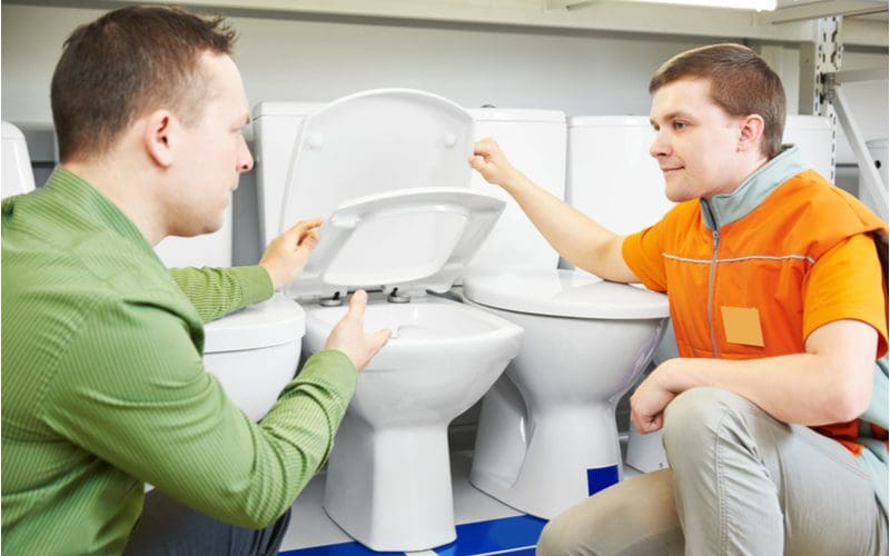 Guy shopping at a hardware store and looking at the best flushing toilet they sell