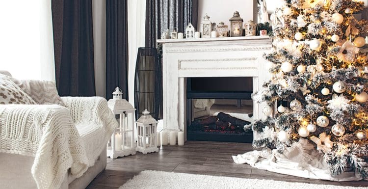 Piece on average height of fireplace mantle featuring a white mantle next to a Christmas tree in a living room with grey hardwood floors