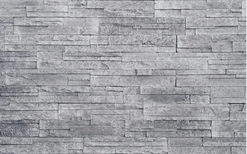 Manufactured stone siding (one of the types of siding) shown in grey color in a close up image