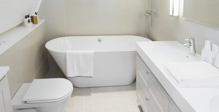 Small bathroom with tub idea featured image featuring a small standalone tub next to a toilet and a slanted wall