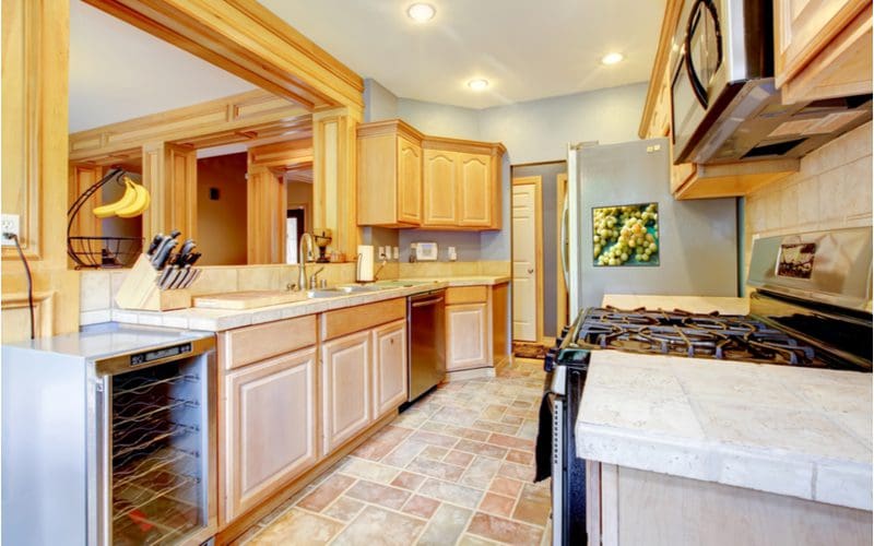 Giant Pass-Through Kitchen With Light Maple Cabinets With White Countertops