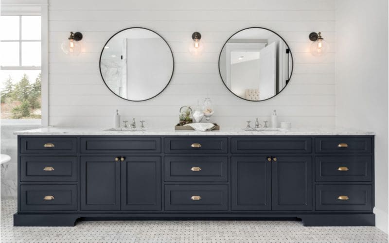 Three sconce lights and two round mirrors above a 60 inch double vanity