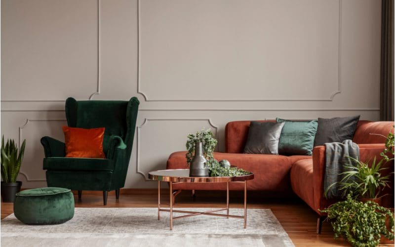 Answer to the question what color furniture goes with gray walls featuring an orange sofa with gold accent pieces