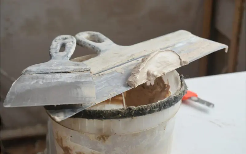 One of the many types of drywall mud below a putty knife