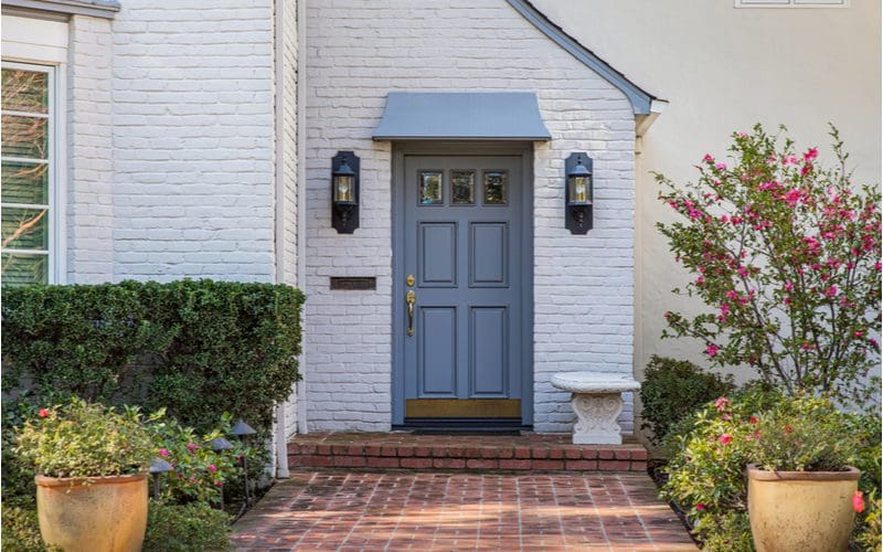 Muted blue front door on a white Tudor-style home