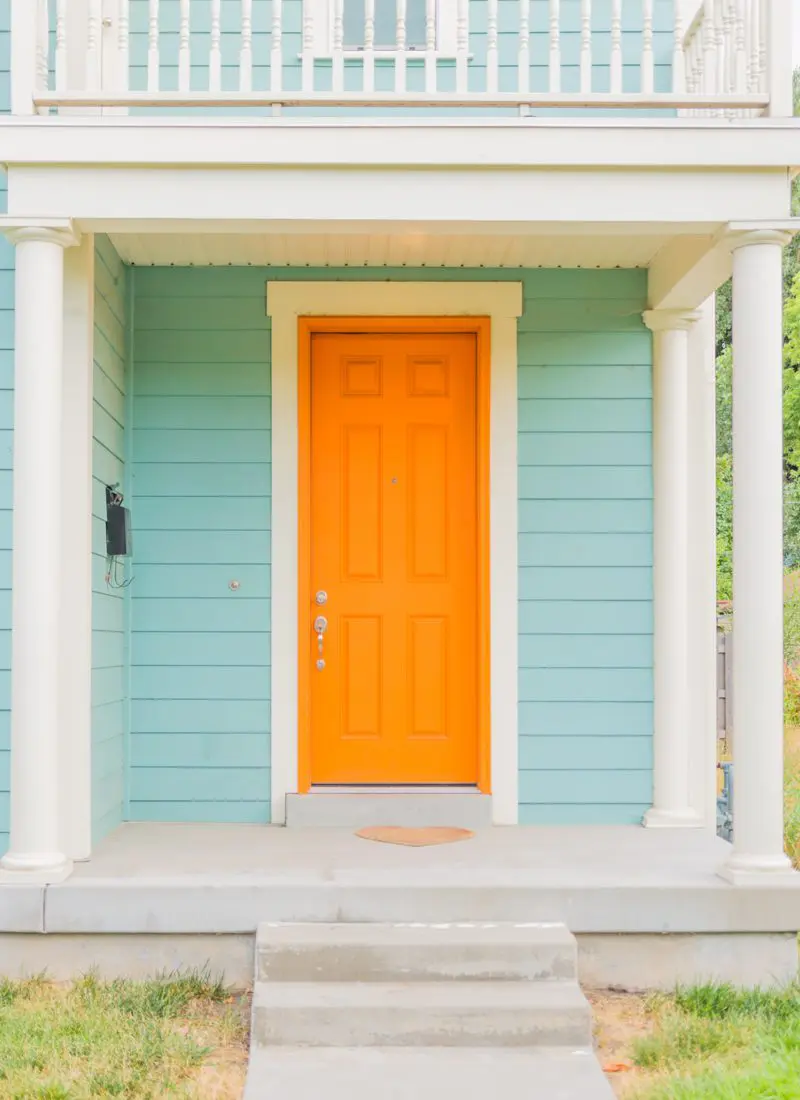 Bright orange front door color for a blue house