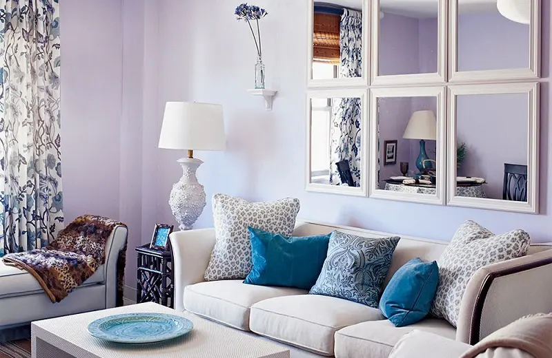 Lavender wall and cobalt blue pillows on a white sofa