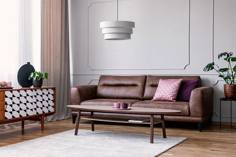 Dark brown leather sofa with pink pillows