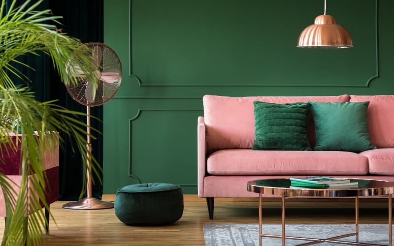 Copper lamp and table in a green living room interior matched with pink sofa