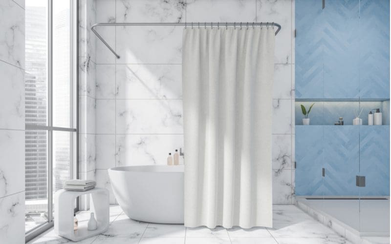 Homeowner using a shower curtain to cover tile in a blue and greay bathroom