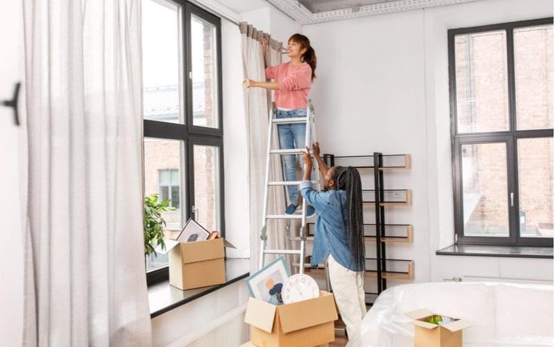 Woman using one of the most popular ways to hang curtains while standing on a ladder