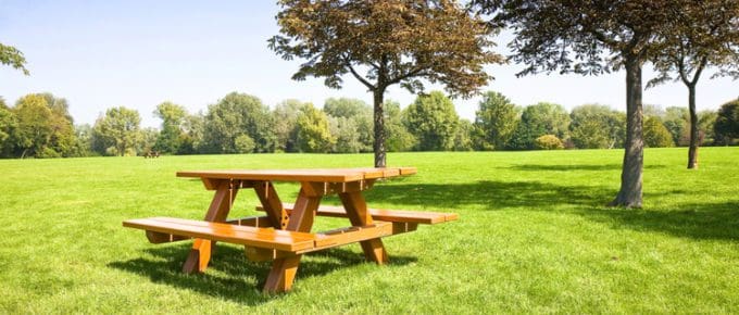 Featured image for a piece on picnic table dimensions with a table sitting on a green lawn