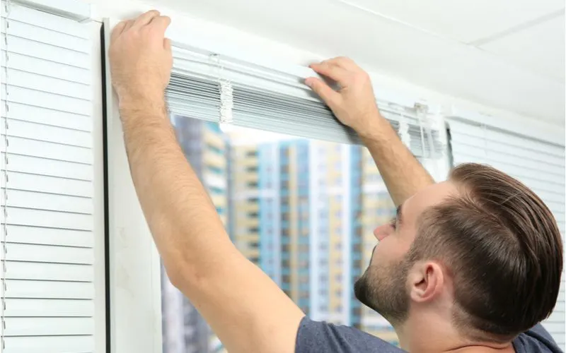 Guy installing no-drill blinds on a window
