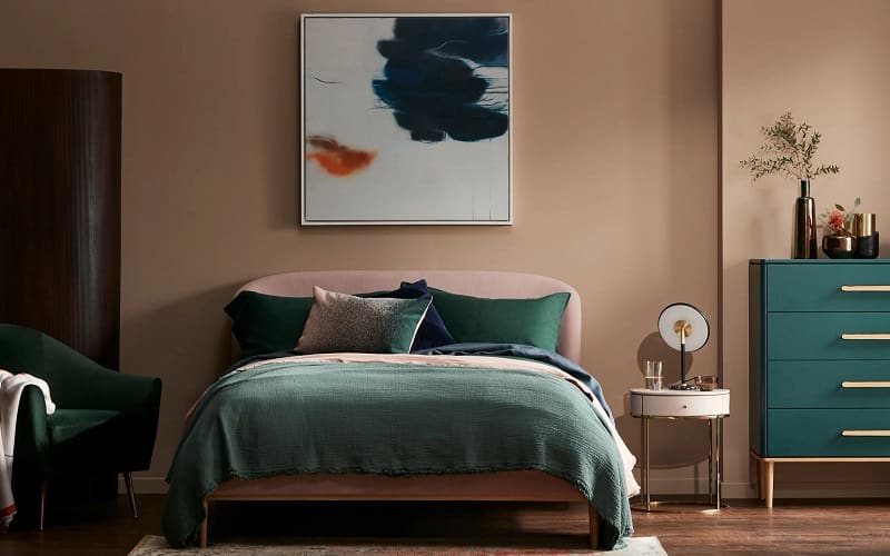 Peach wall and forrest green bedsheets bedroom decoration idea