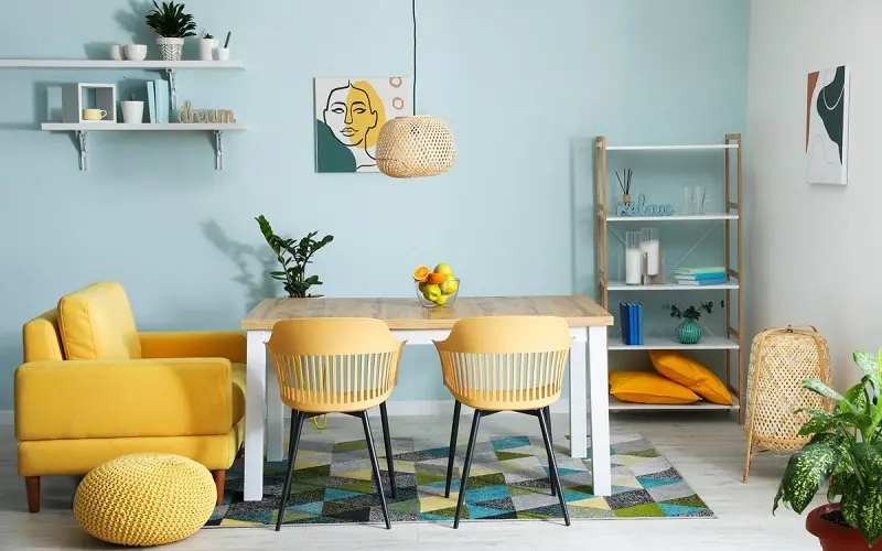 Light blue wall and pastel color combination with dusty yellow chairs and pastel rug