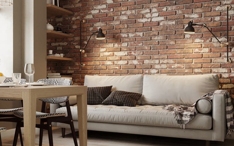 Living room corner with beige sofa and a brown brick wall