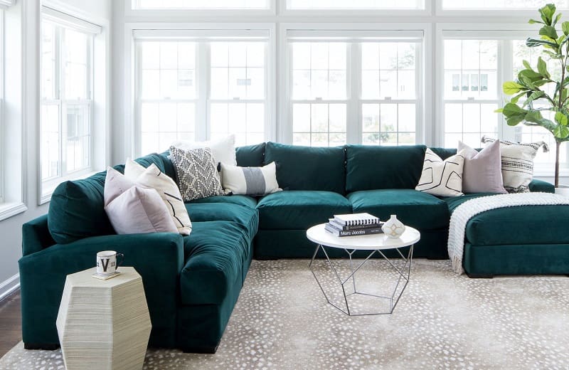 White room with lots of windows and dark green sofa