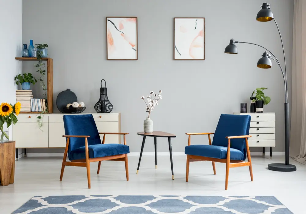 Chairs with a black lamp and light grey flooring and paint, several colors that go with royal blue