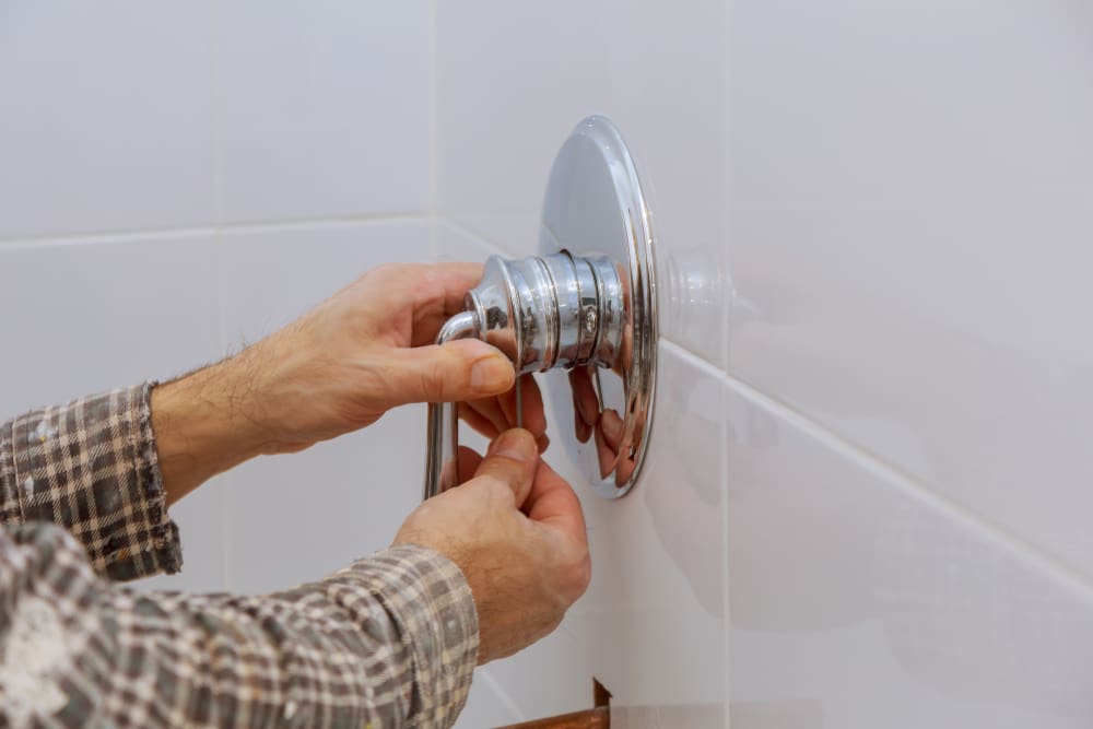 Plumber fixing a shower handle on a single-handle mixer in a shower for a piece on the average shower handle height