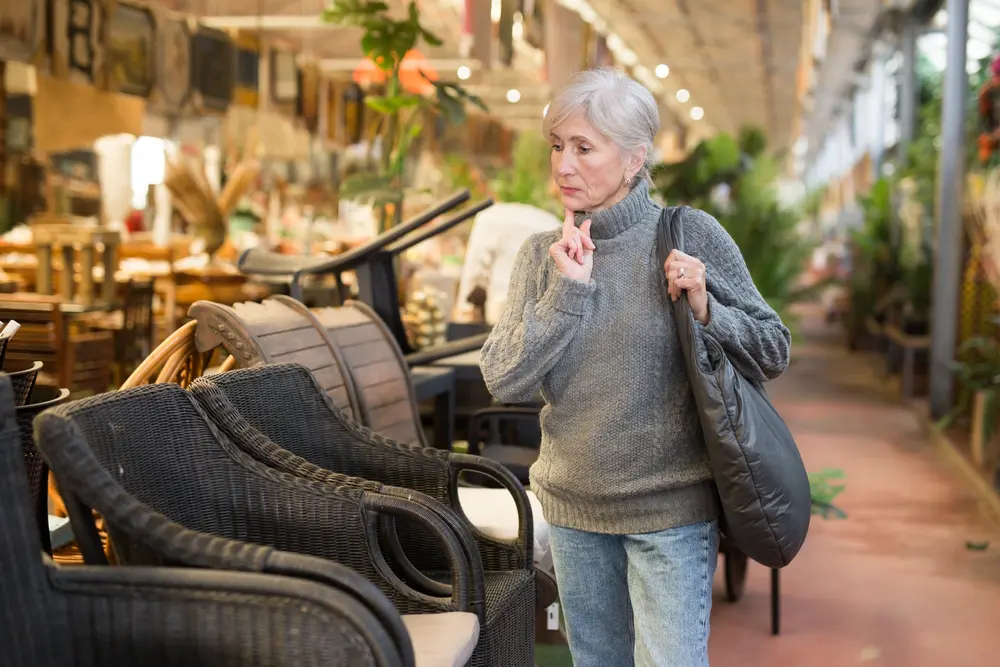 Grey haired woman choosing from various types of chairs in a store