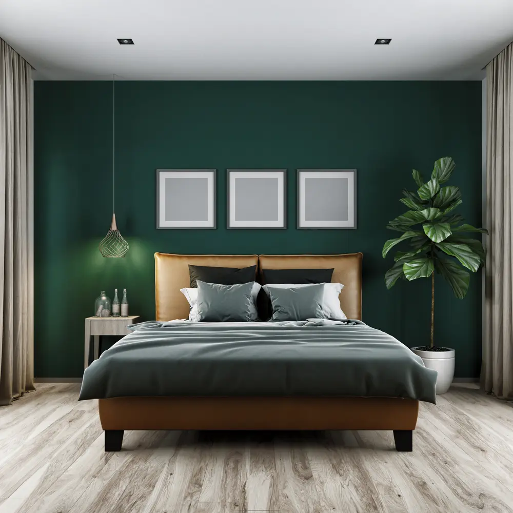 Photo of a hunter green bedroom wall with a bed and square picture frames above for a piece on the best colors to go with dark green interiors