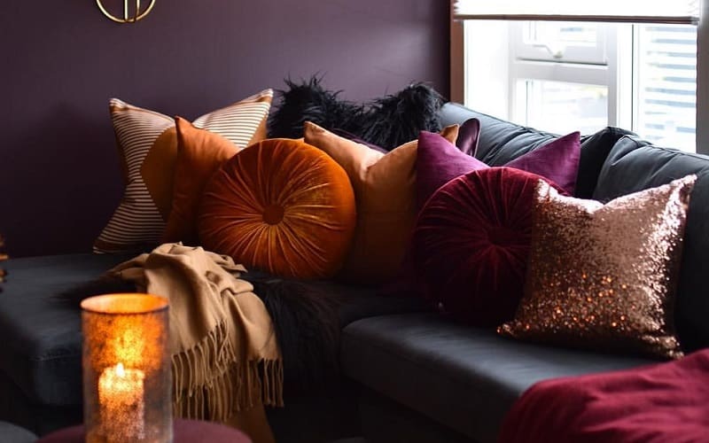 Plum toned living room combined with burnt orange pillows